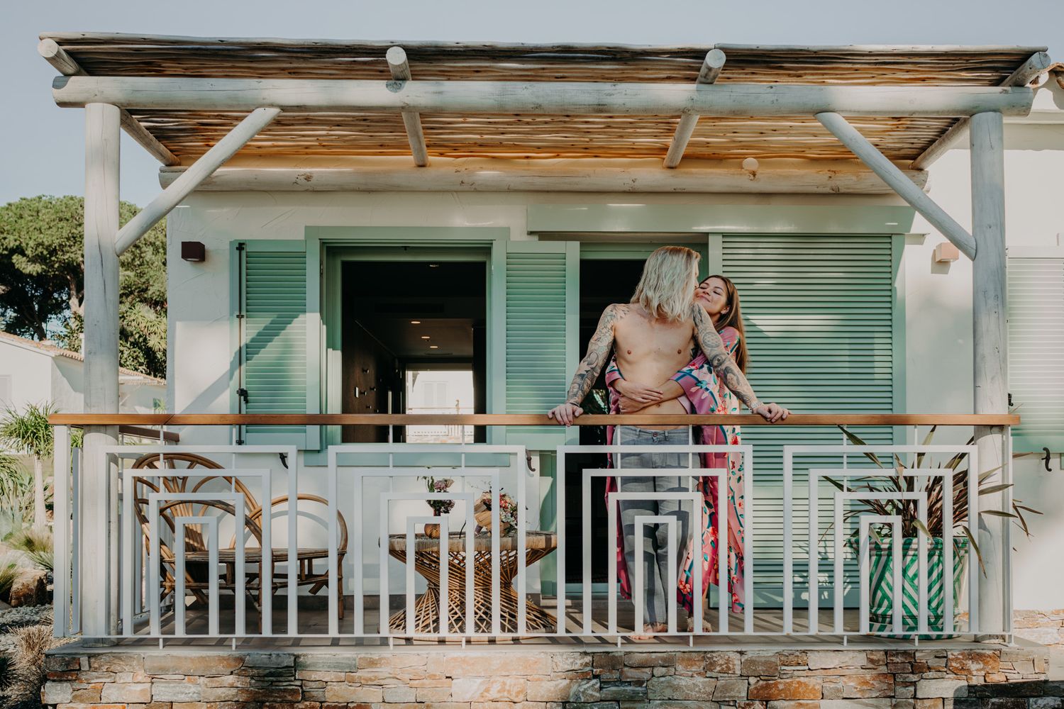 A cozy wooden porch with mint green shutters welcomes guests to a charming seaside cottage.
