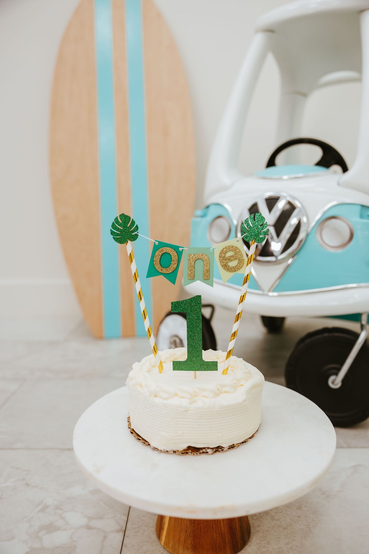 Beach-themed first birthday setup with surfboard and teal VW bus decor.