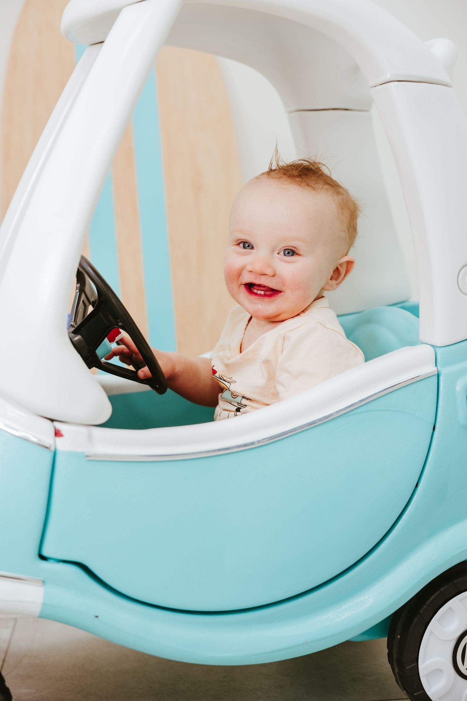A playful moment inside a light blue toy VW bus ride-on car.