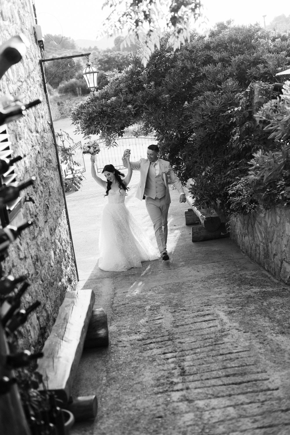 A black and white shot of newlyweds joyfully walking down a stone pathway.