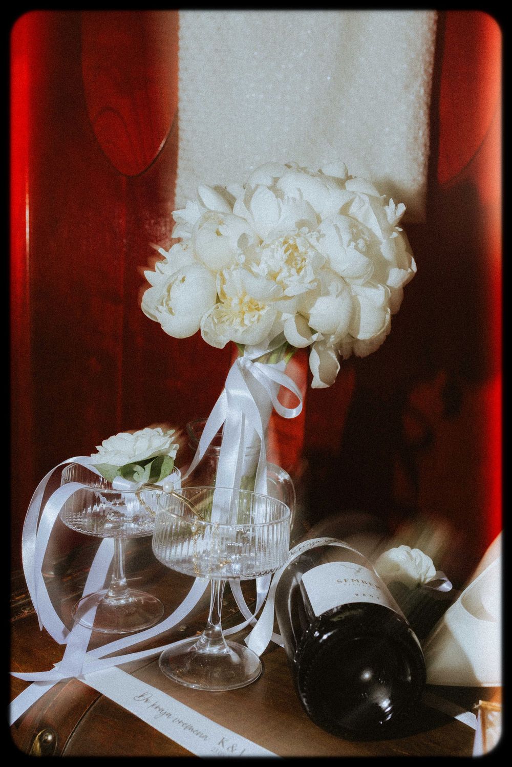 White peonies arranged in glass vases against a red backdrop create an elegant floral display.