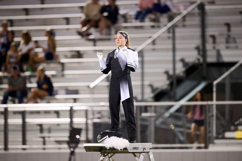 Marching band performers create formations on a football field during a halftime show performance.