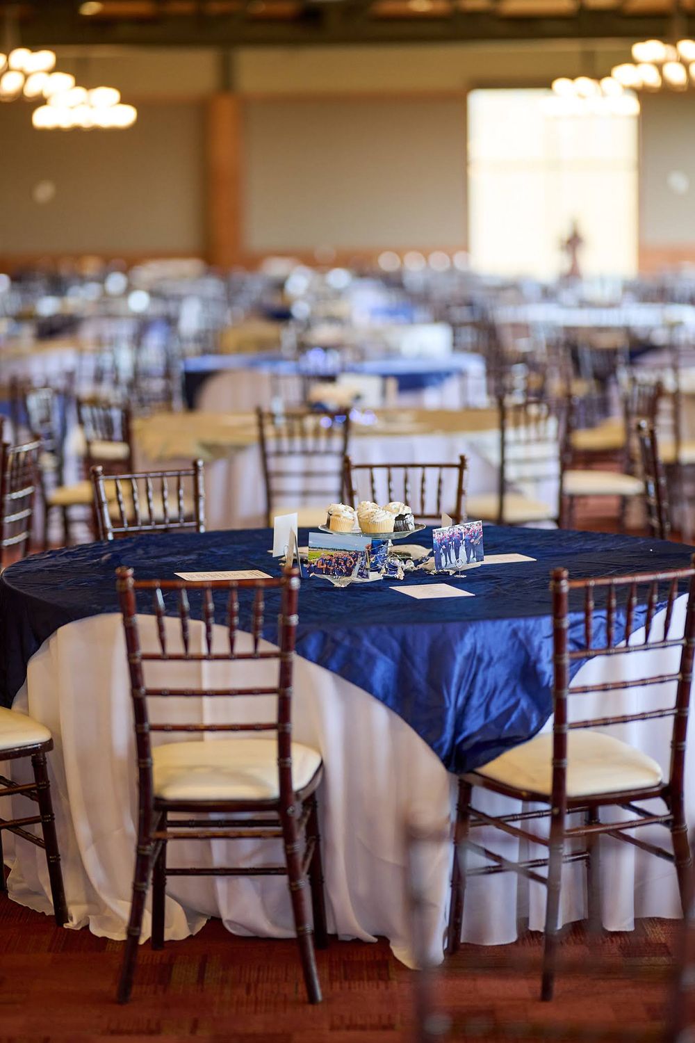 Elegant wedding reception setup with navy blue tablecloths and wooden Chiavari chairs.