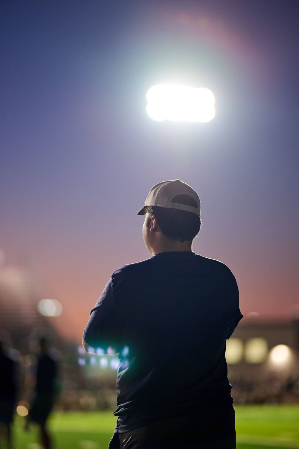 Stadium lights illuminate the night sky creating a dramatic silhouette against the sunset.