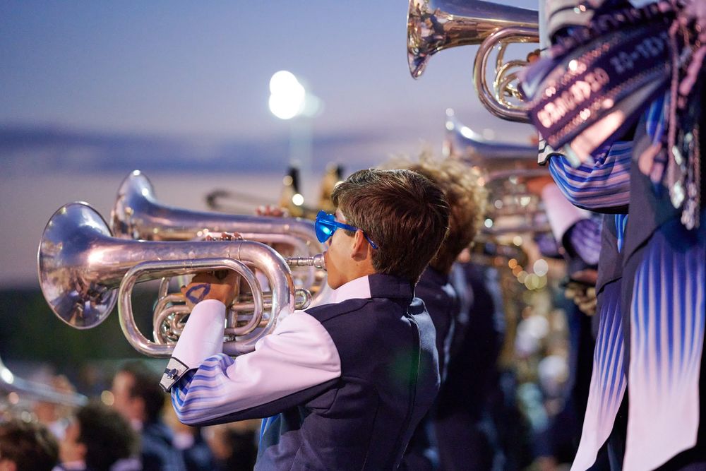 Musicians play brass instruments during twilight performance with moon visible in background.