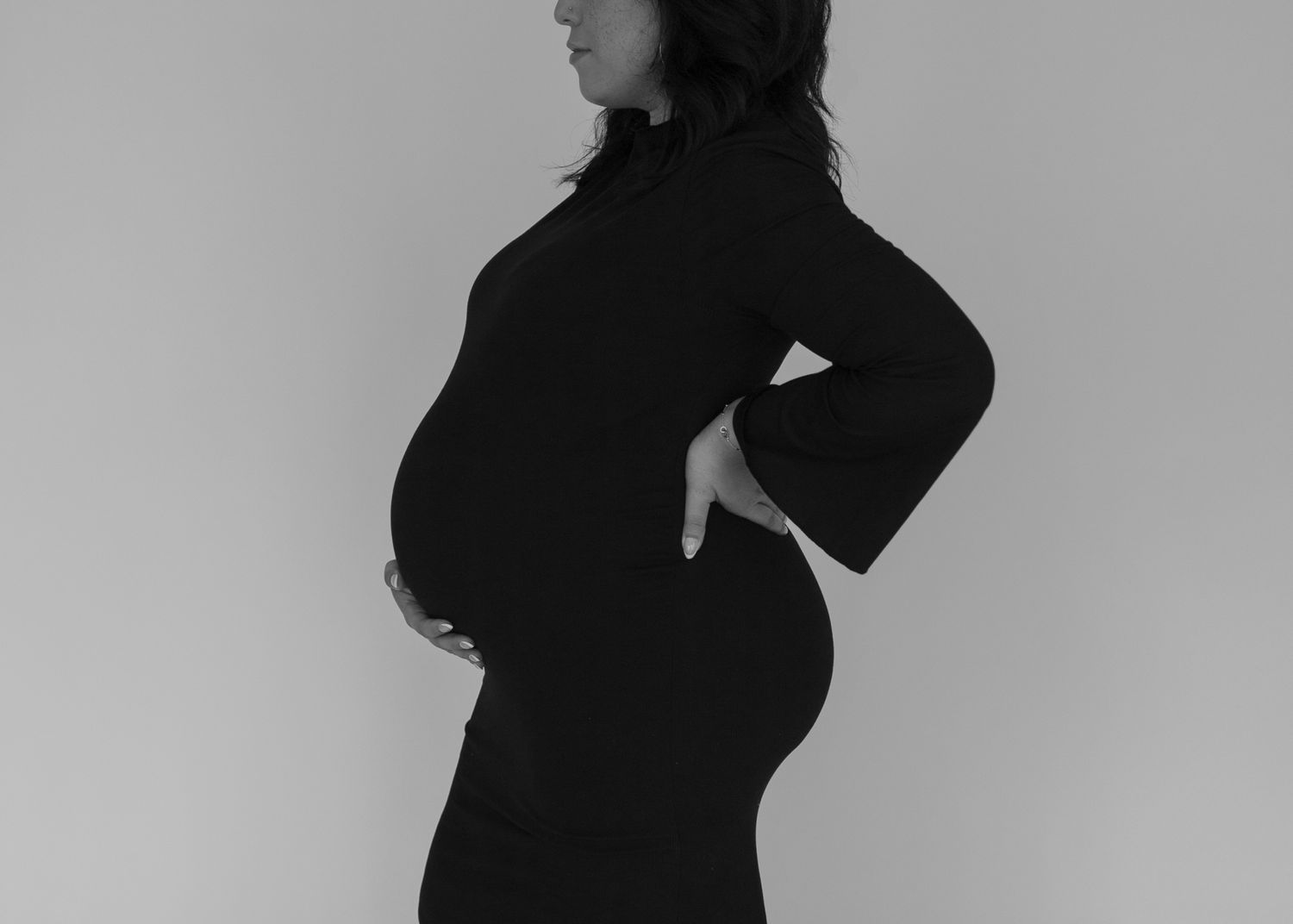 A silhouette of a pregnant woman in black against a gray background.