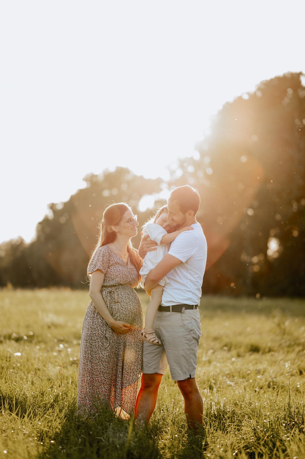 Babybauchshooting mit Mutter, Vater Kind auf einer Wiese, die sich im Arm halten Mengen Jovanna Burkard KWICKSHOT