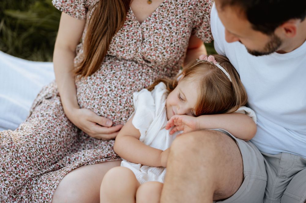 Babybauchshooting und Nahaufnahme Kuschelmoment von sitzenden Eltern und ihrer Tochter Mengen Jovanna Burkard KWICKSHOT
