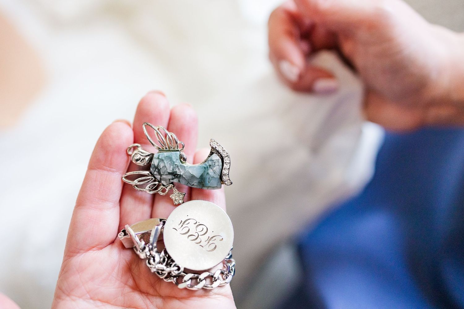 A decorative silver key charm being held in someone's palm.