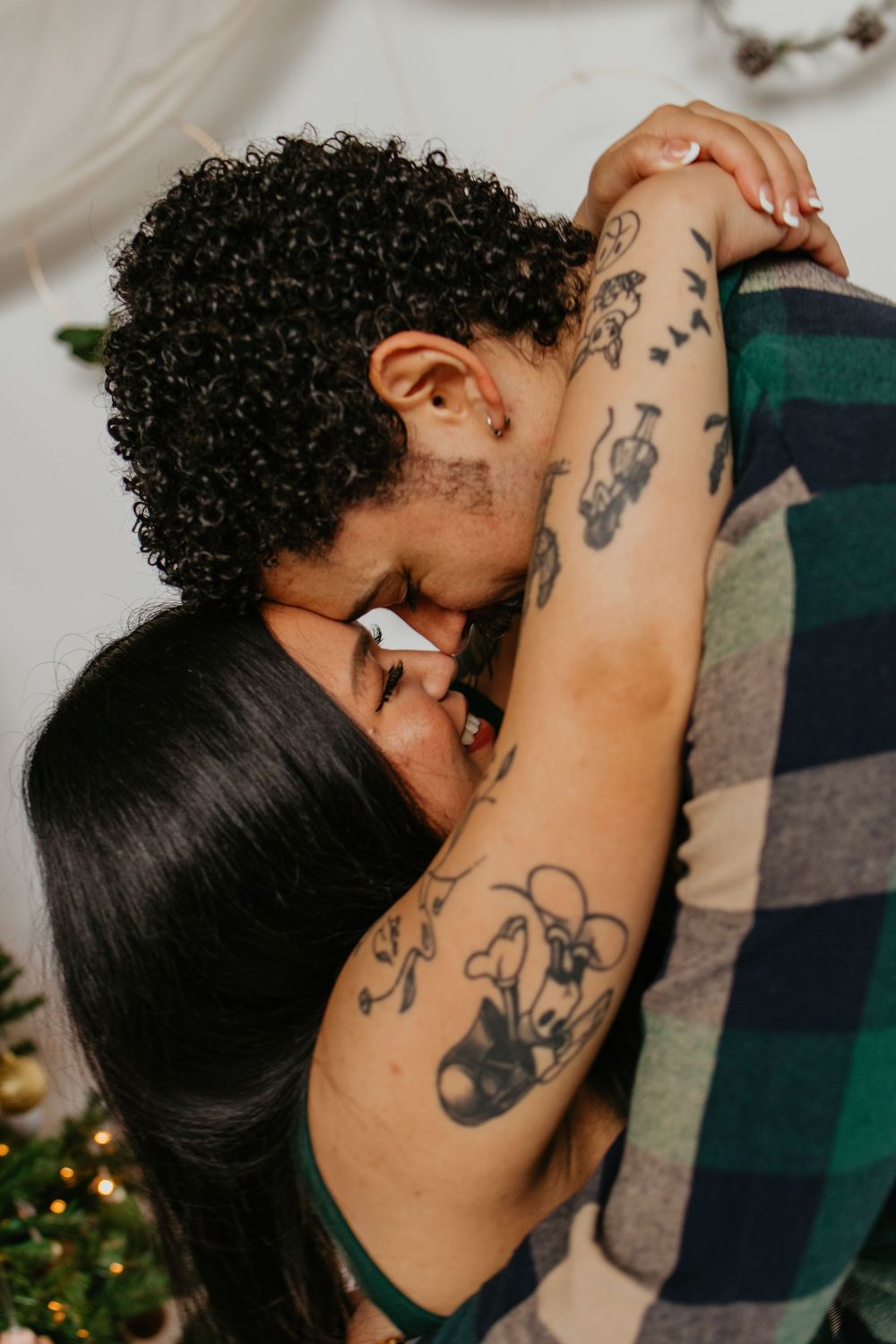 Close-up shot of a couple embracing tenderly, with visible tattoos on their arms.