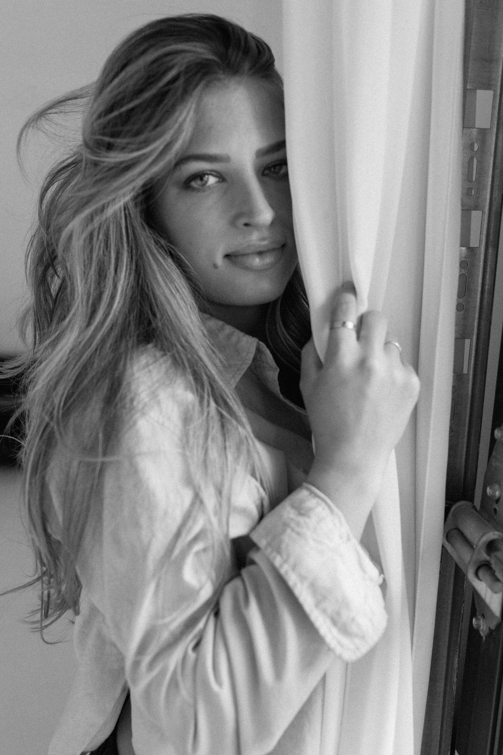 Artistic black and white portrait showing long blonde hair and natural lighting by a window.