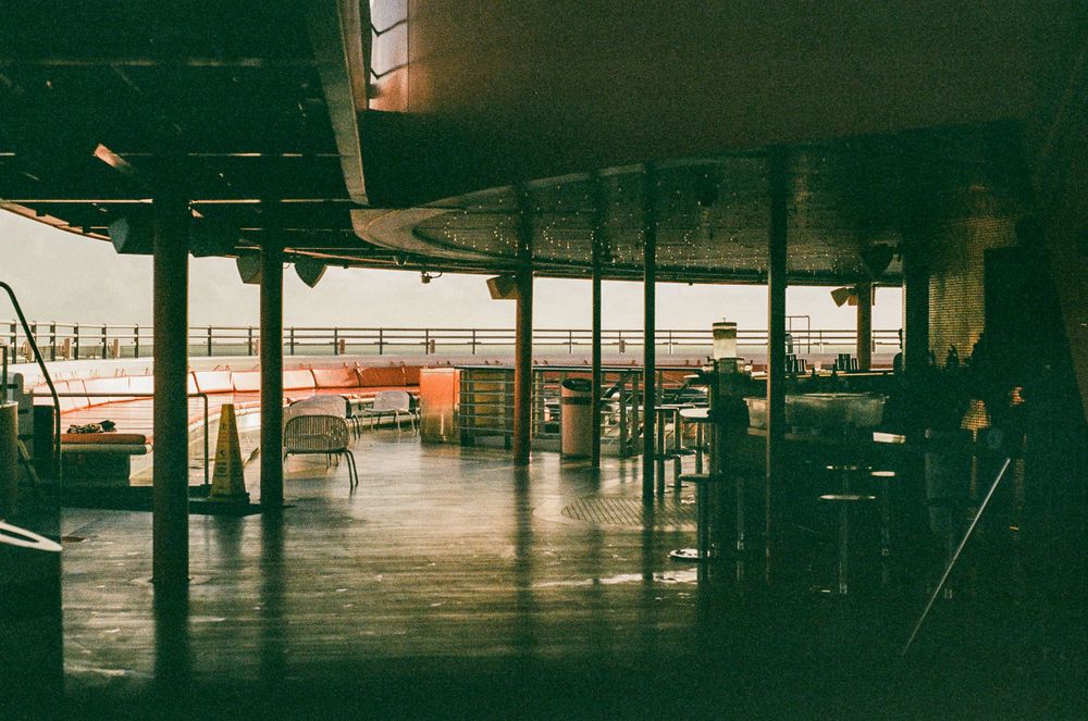 Empty indoor walkway with industrial architecture and dark moody lighting.