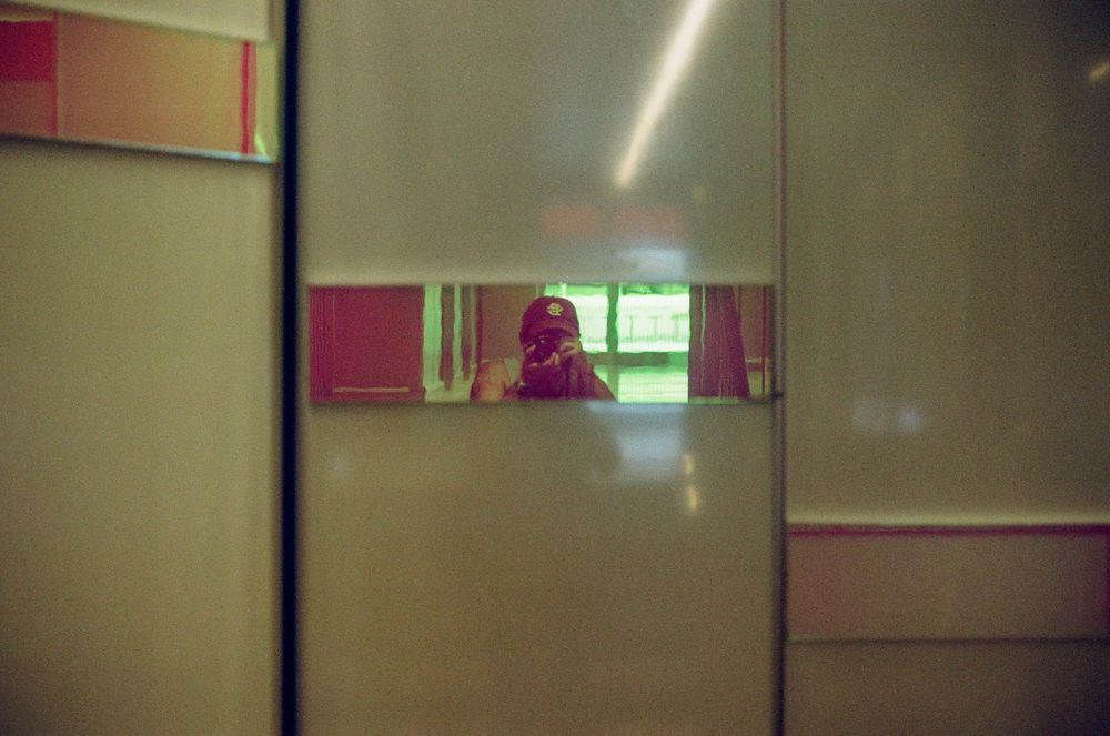 Abstract reflection in pink and green tinted mirrors creating geometric patterns.