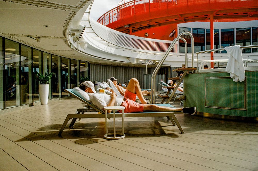 Sun loungers on a cruise ship deck with distinctive orange and white architectural details.