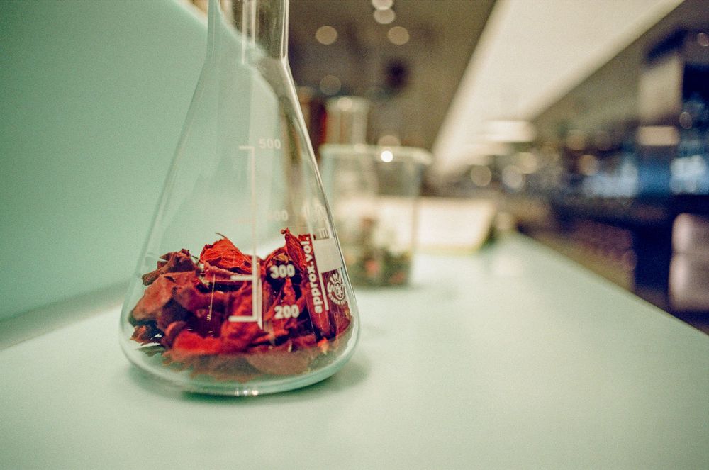 A glass beaker containing red chemical crystals sits on a laboratory counter.