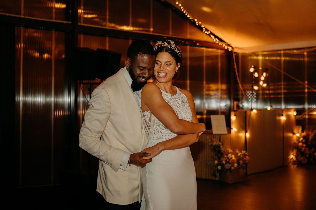 Bride and groom sharing a romantic moment on the dance floor surrounded by warm fairy lights.