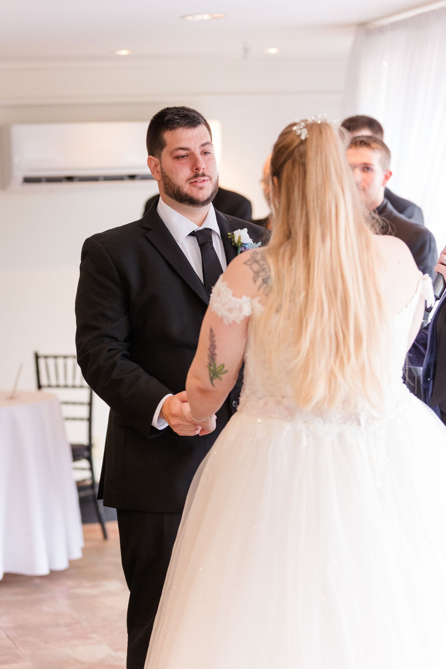 First dance between newlyweds in a bright white reception venue with elegant decor.