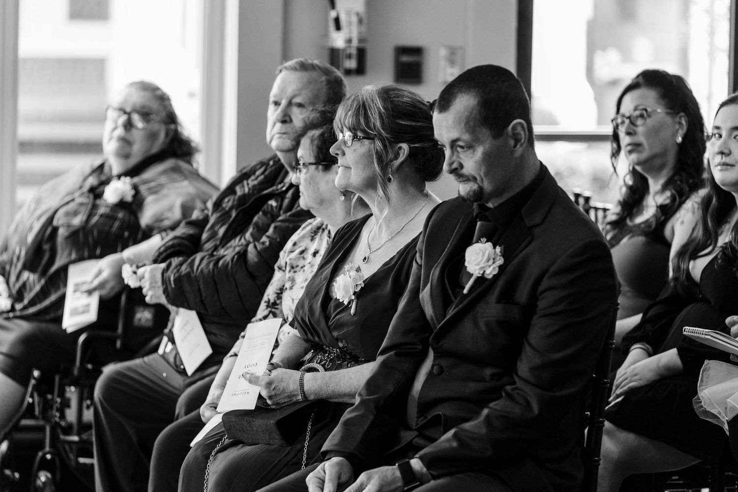 A diverse audience sits attentively in rows during a presentation or performance in a dimly lit venue.