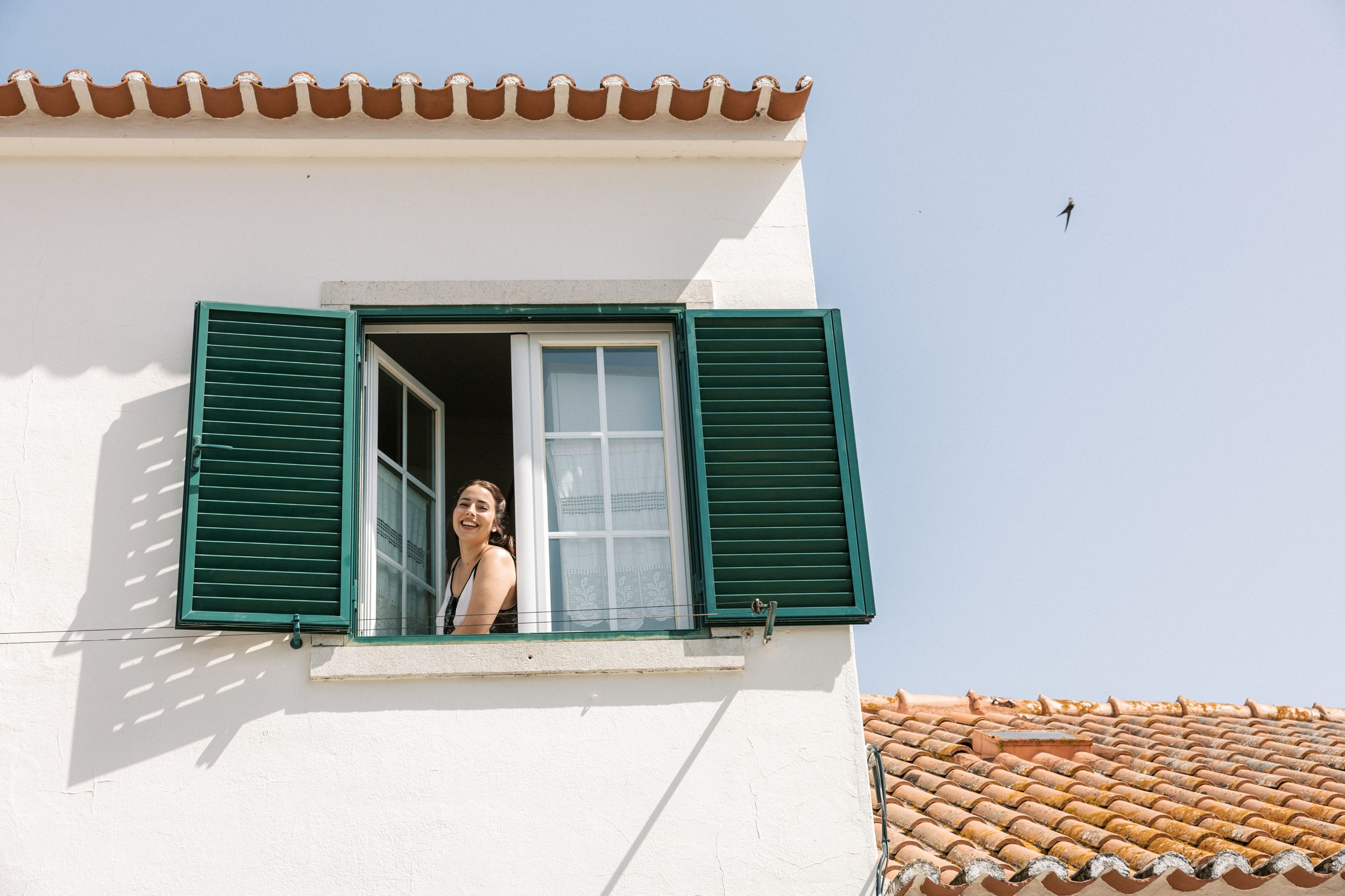 Bride smiling at window of traditional Portuguese house in Portugal