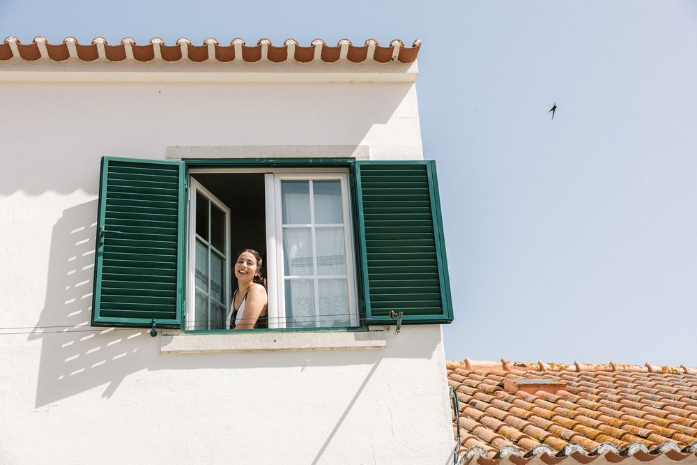 Bride smiling at window of traditional Portuguese house in Portugal