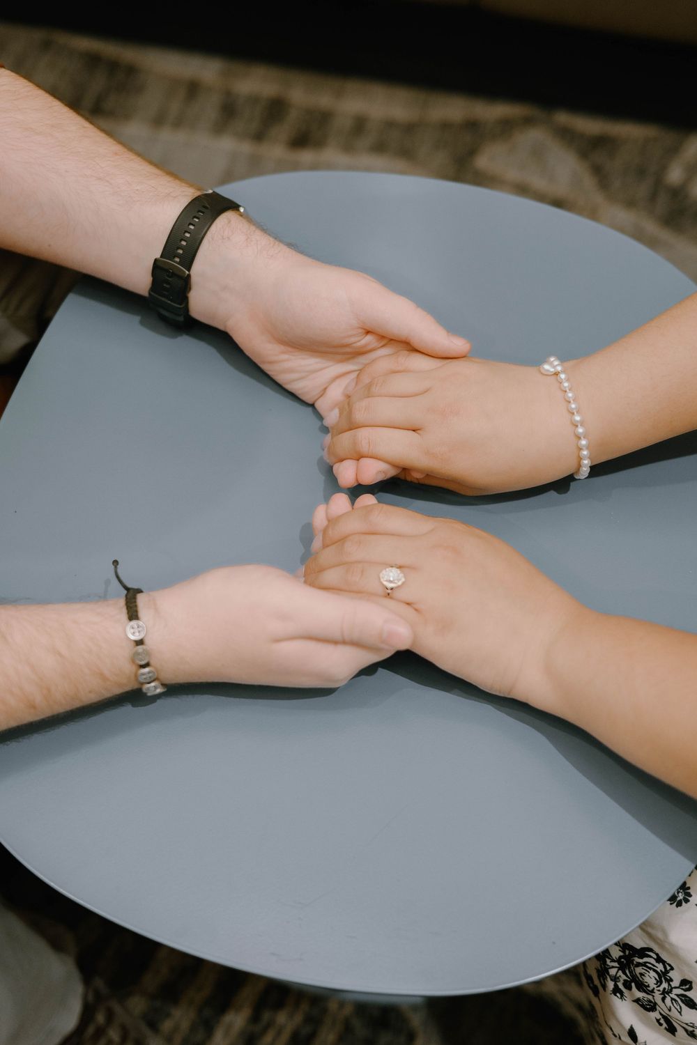 Close-up shots of hands holding and touching each other against a gray background.