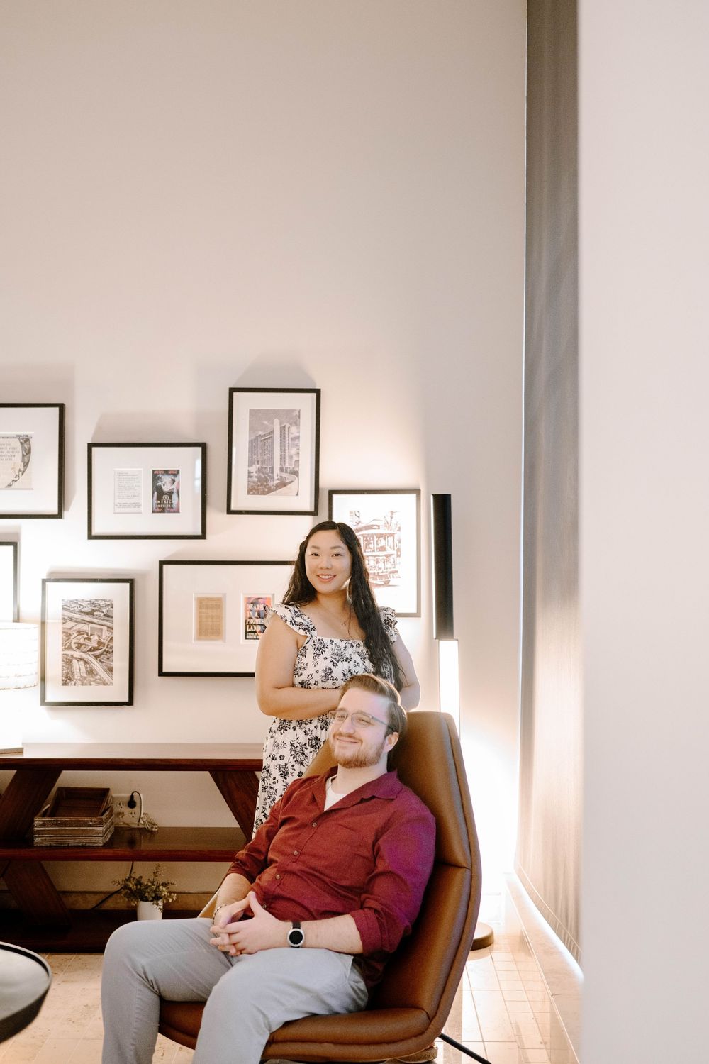 Gallery space with framed artwork and two people resting in a leather chair.
