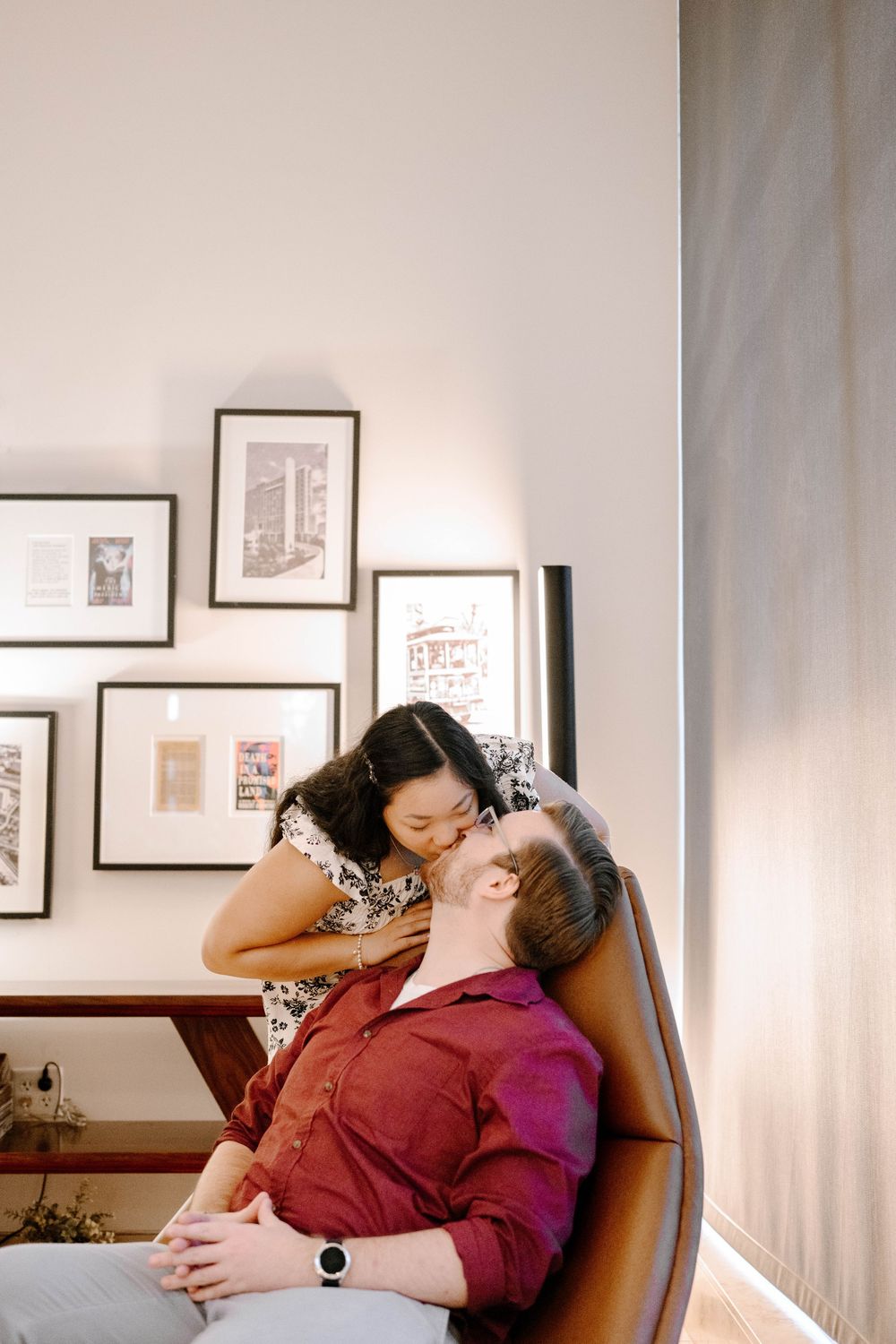 Couple embracing in an art gallery with black and white photographs on display.