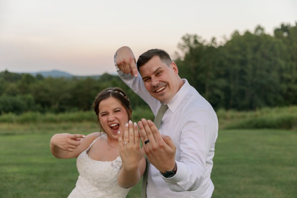 Joyful newlyweds showing off their rings in outdoor celebration.