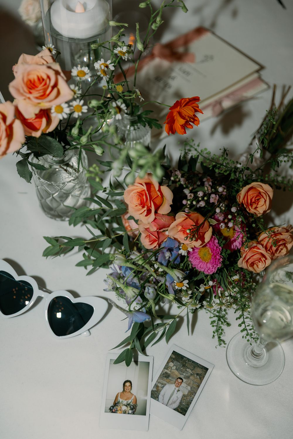 Wedding reception table with peach roses, wildflowers, and polaroid photos.