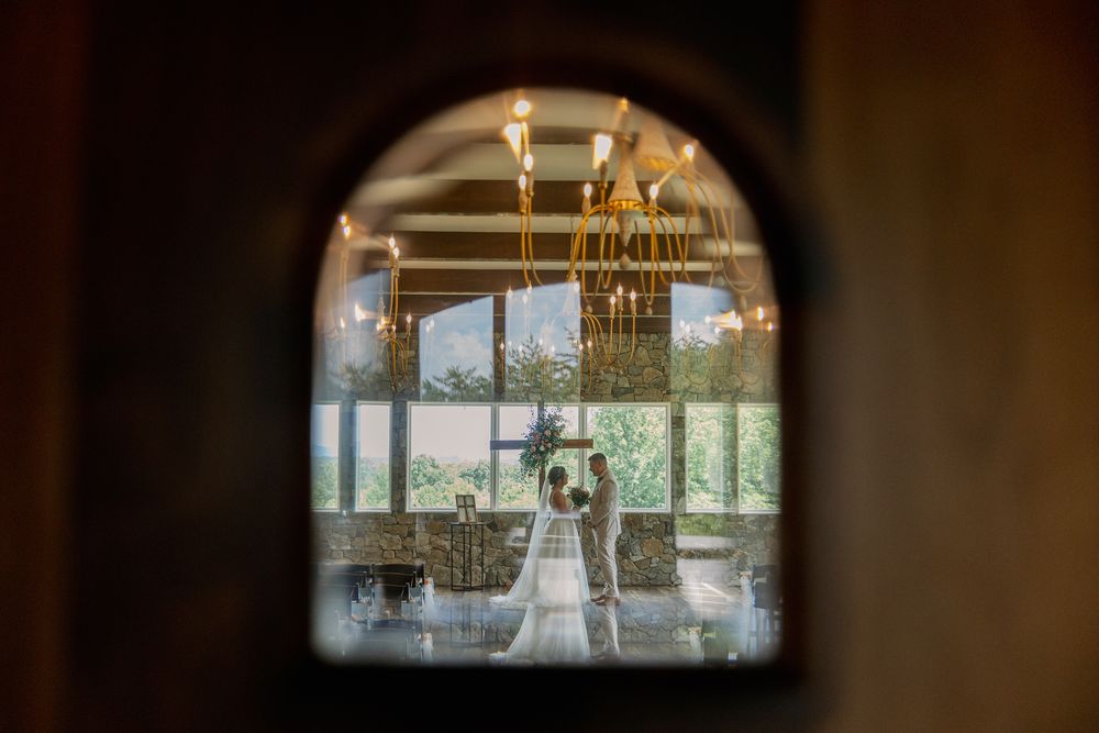 Romantic wedding venue framed through an arched doorway with elegant chandelier and natural lighting.