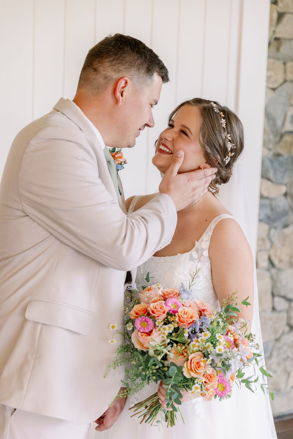 Tender moment between newlyweds with bride holding colorful spring bouquet.