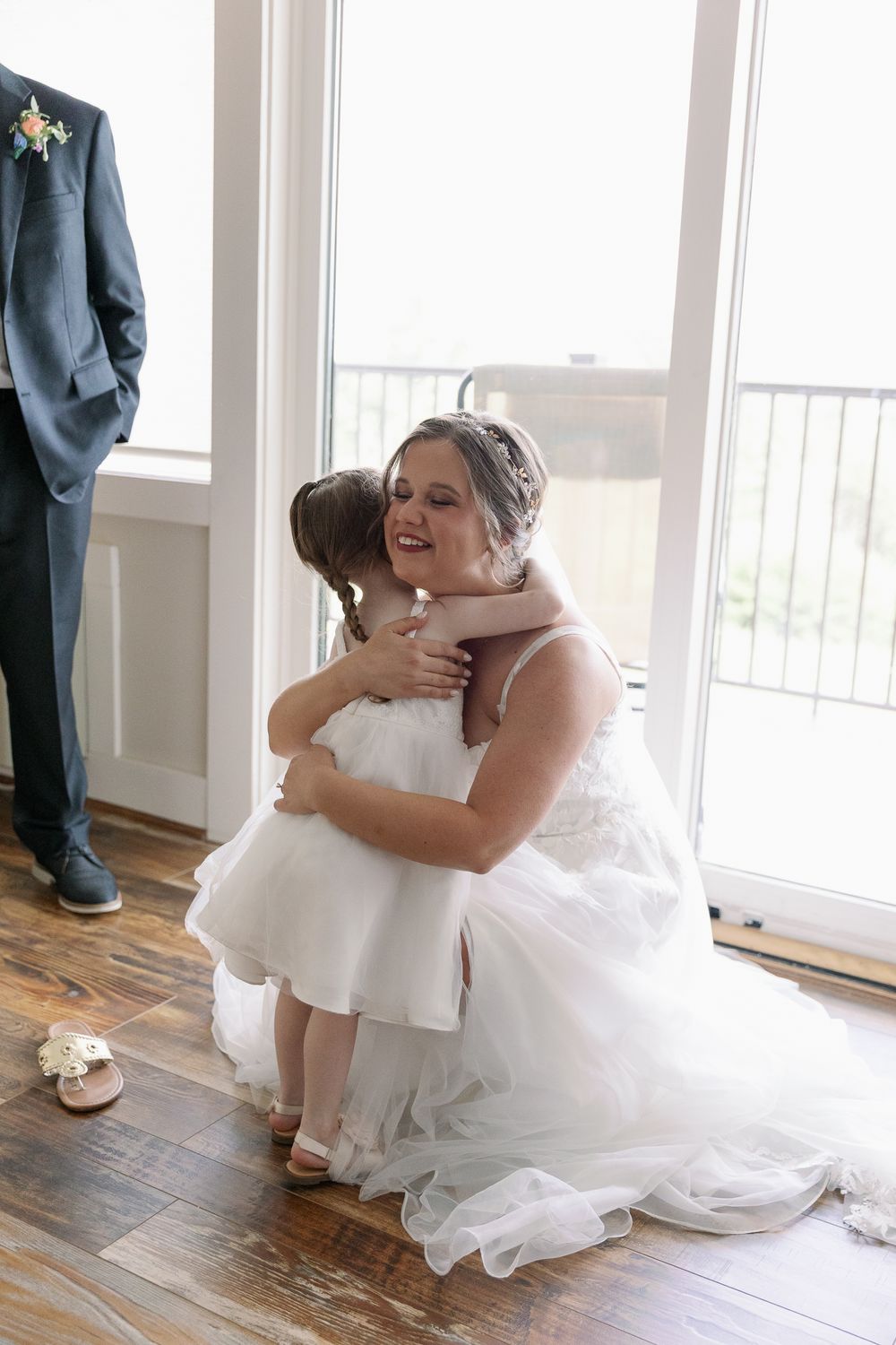 Emotional moment captured on hardwood floors near bright windows.