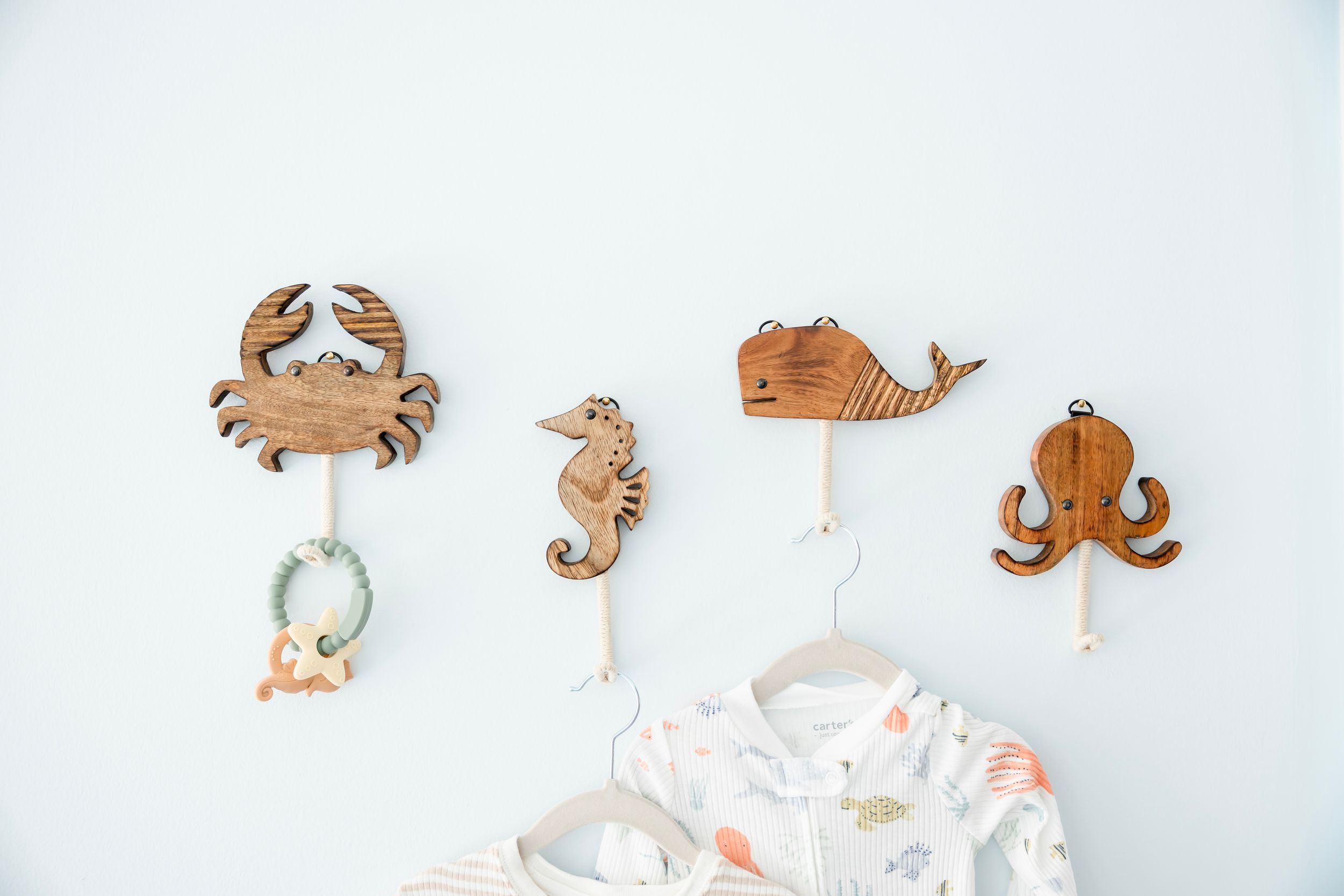 Small wooden sea creatures and animal toys arranged in a row on a white background.