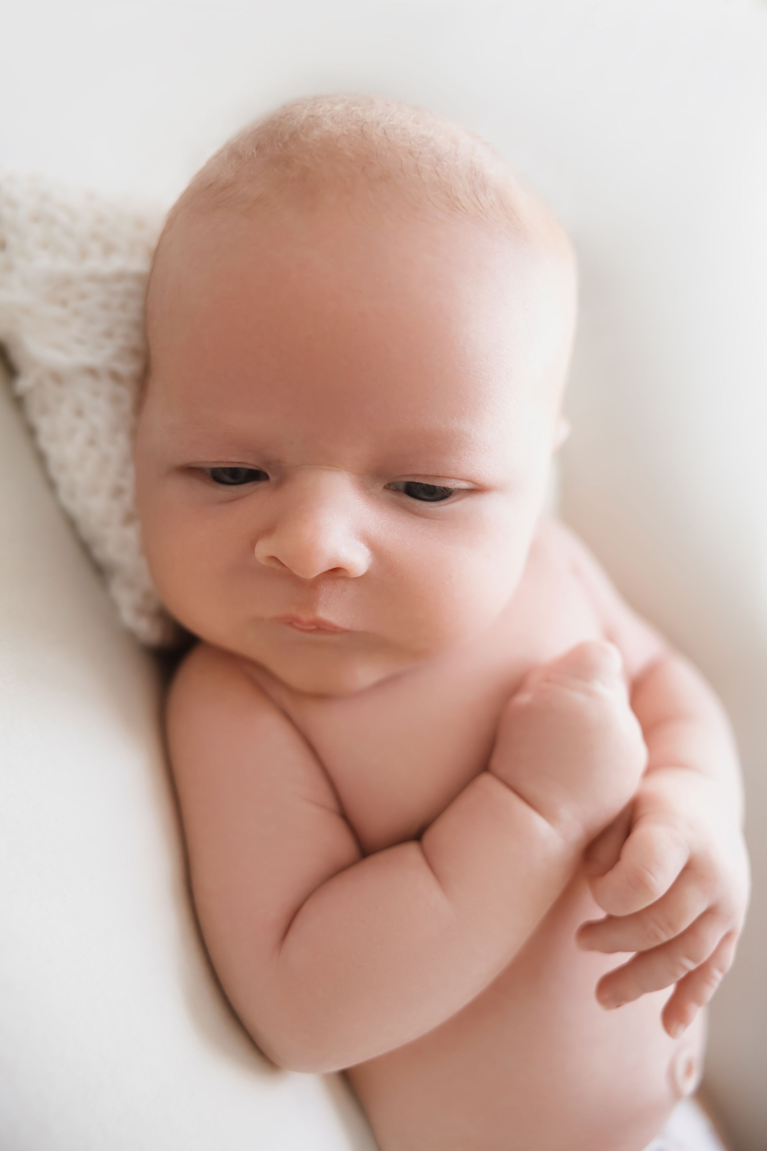 Close-up artistic portraits of a sleeping newborn baby in soft, minimalist white tones.
