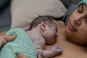 A tender moment between parent and newborn baby lying together on a soft surface.