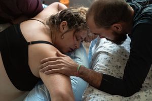 A tender moment during a water birth as a couple embraces in a birthing pool.