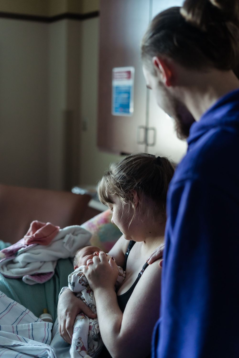 A tender moment in a hospital room as a newborn baby is cradled while receiving care.