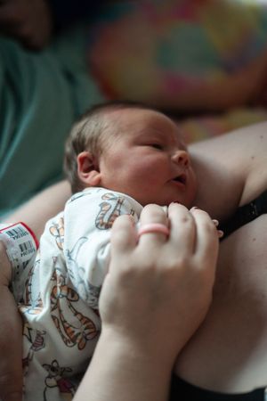 A baby drinks milk from a bottle decorated with animal patterns while lying down.