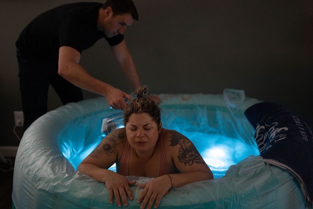A massage therapist performs a therapeutic back massage treatment on a client in a dimly lit spa room.