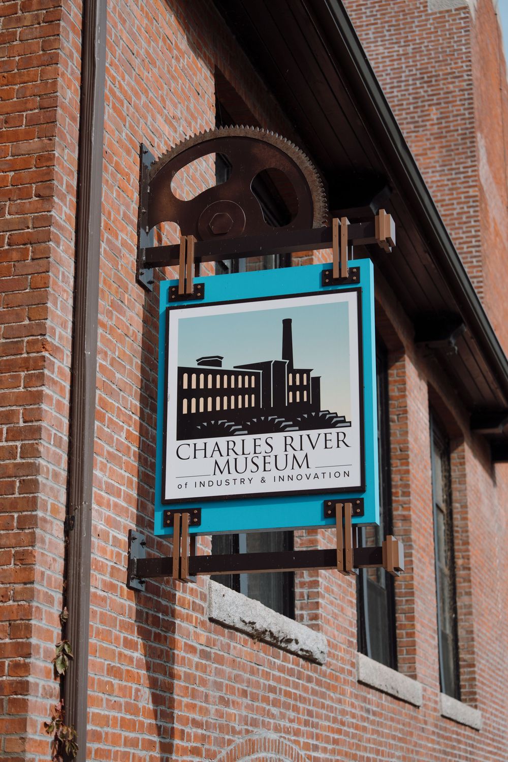 Exterior view of Charles River Museum with blue signage mounted on historic brick building facade.
