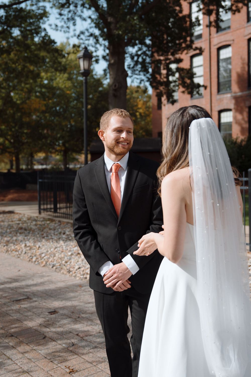 A series of intimate first look moments between a bride and groom outside a brick building.