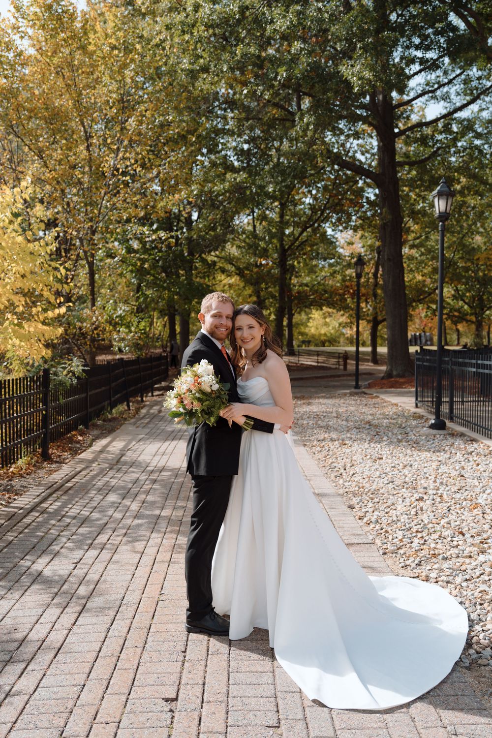 A romantic wedding photo sequence captured on a stone pathway surrounded by autumn trees and golden foliage.