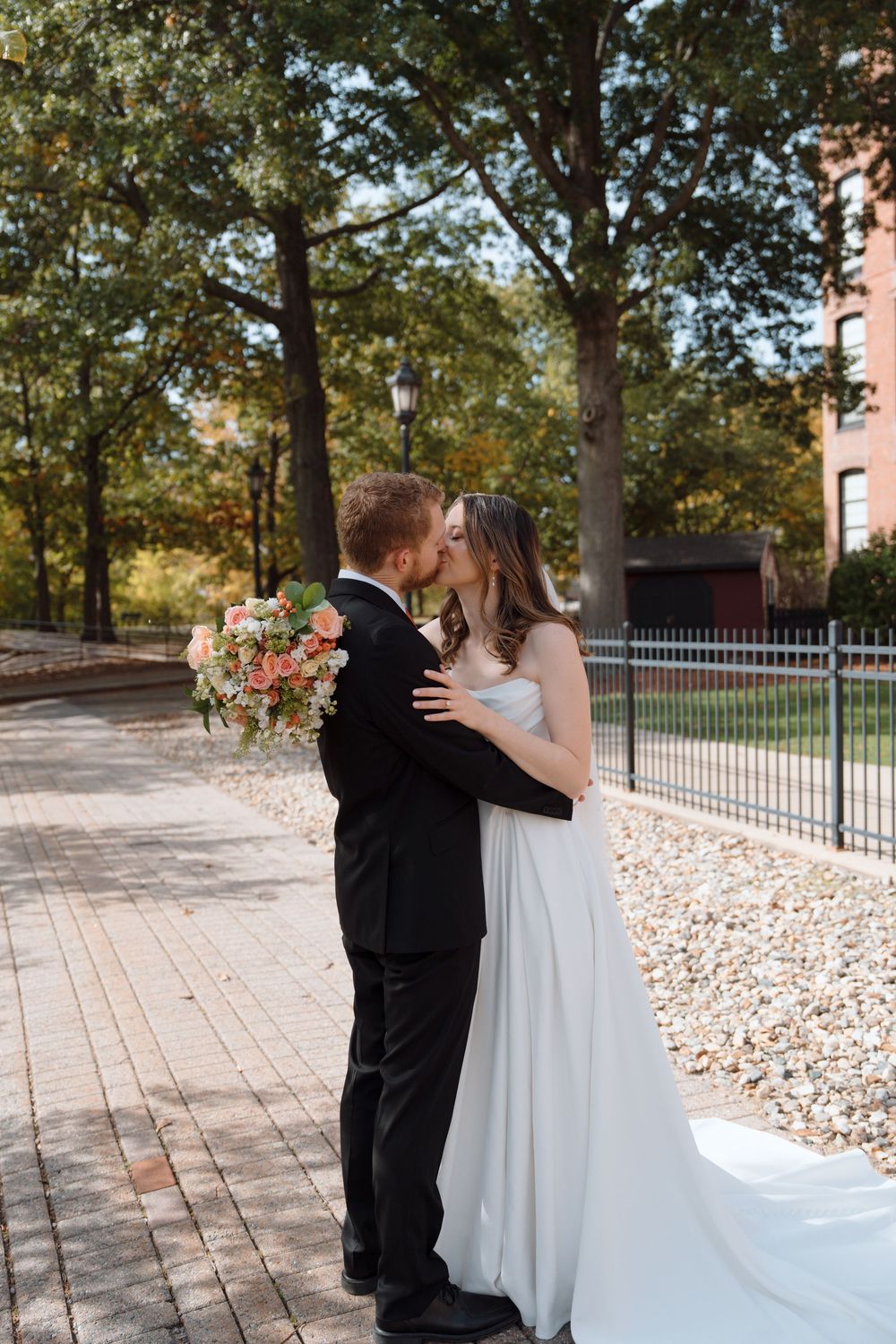 A romantic first look sequence between newlyweds on a brick paved walkway surrounded by autumn trees.