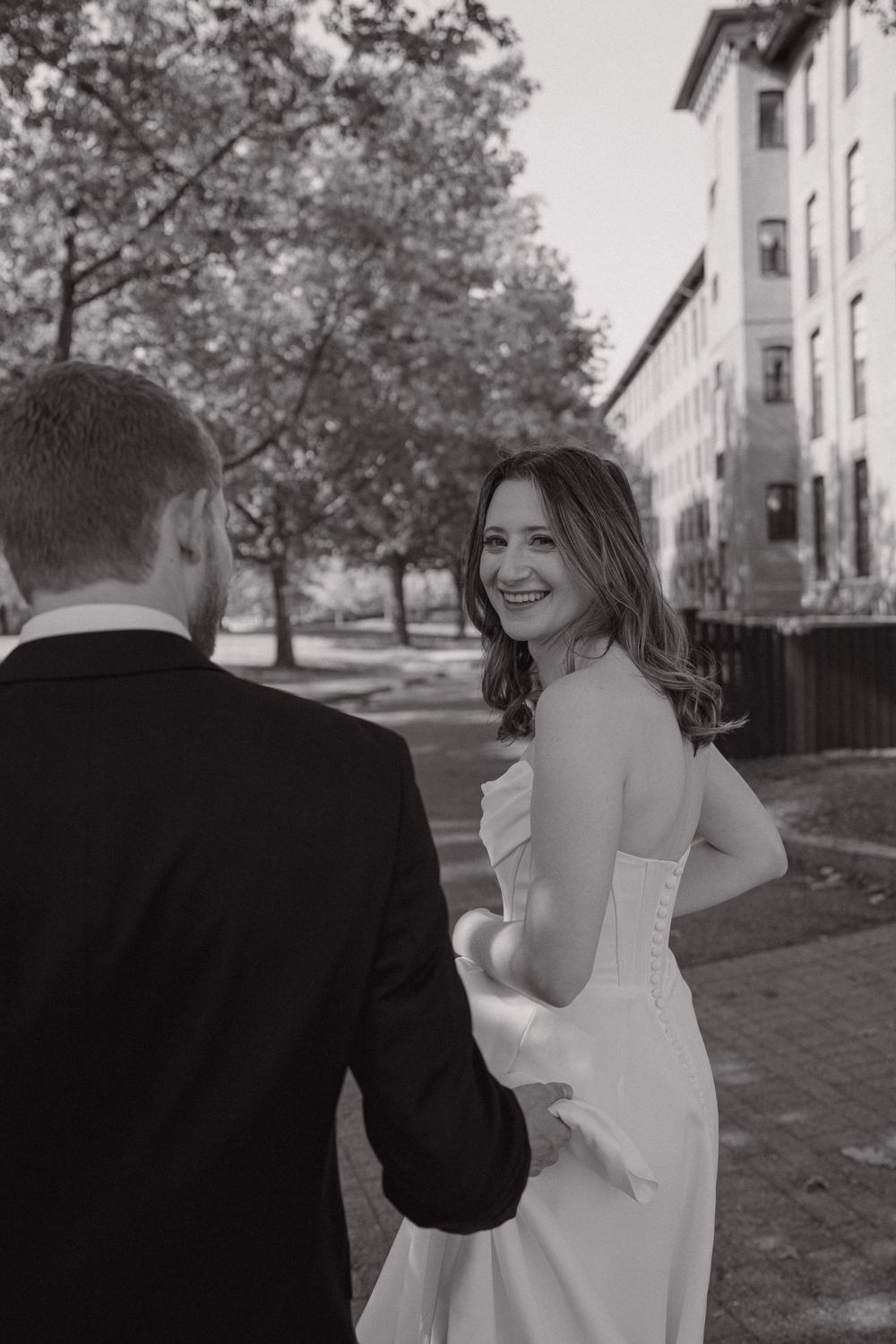 A romantic black and white photo series showing a couple in formal attire walking together outdoors on a sunny day.