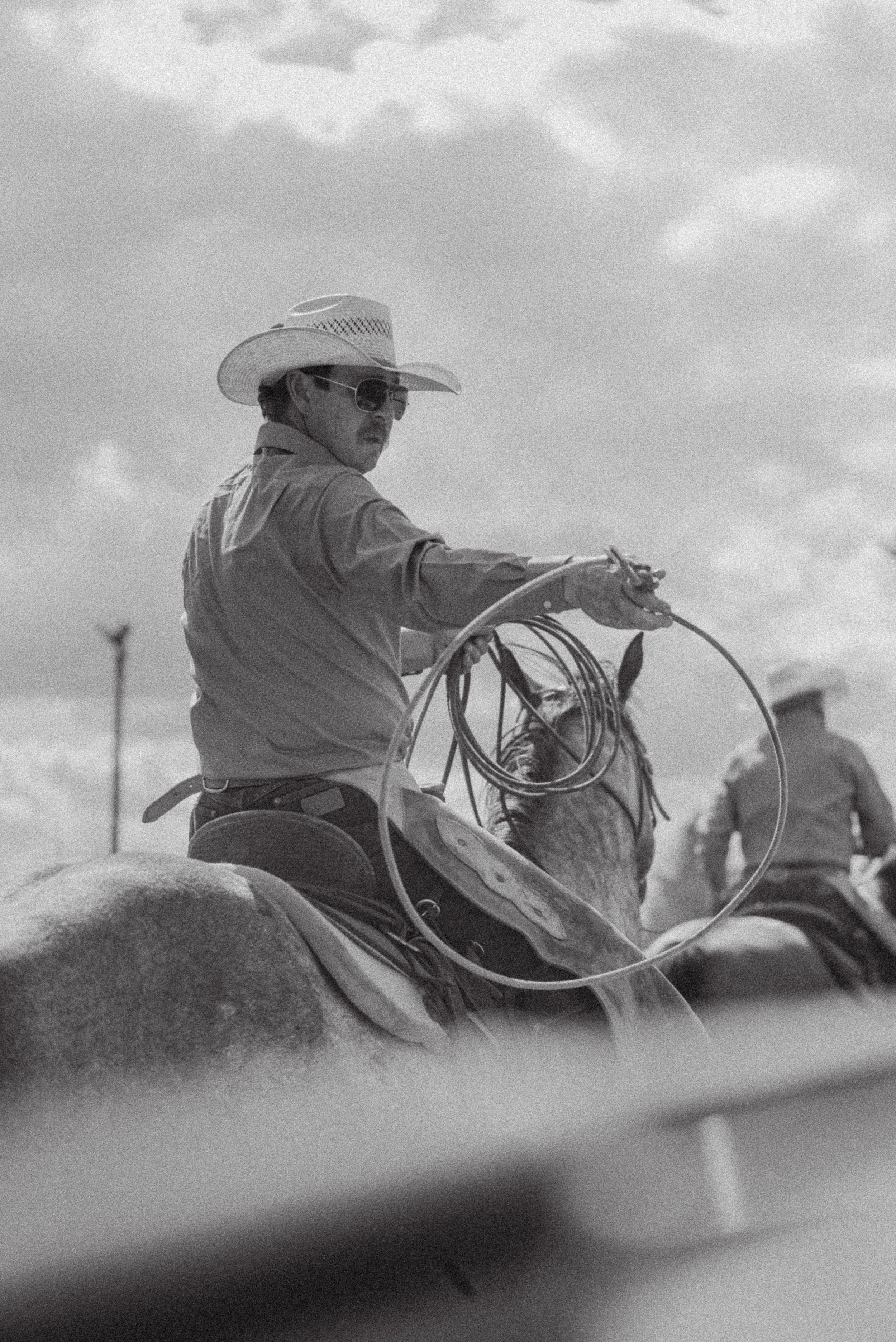 A black and white sequence of a cowboy riding a horse in silhouette against a cloudy sky.