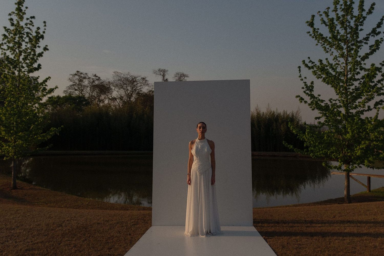 A series of outdoor photos shows someone in a white dress posing against a minimalist white wall at sunset.