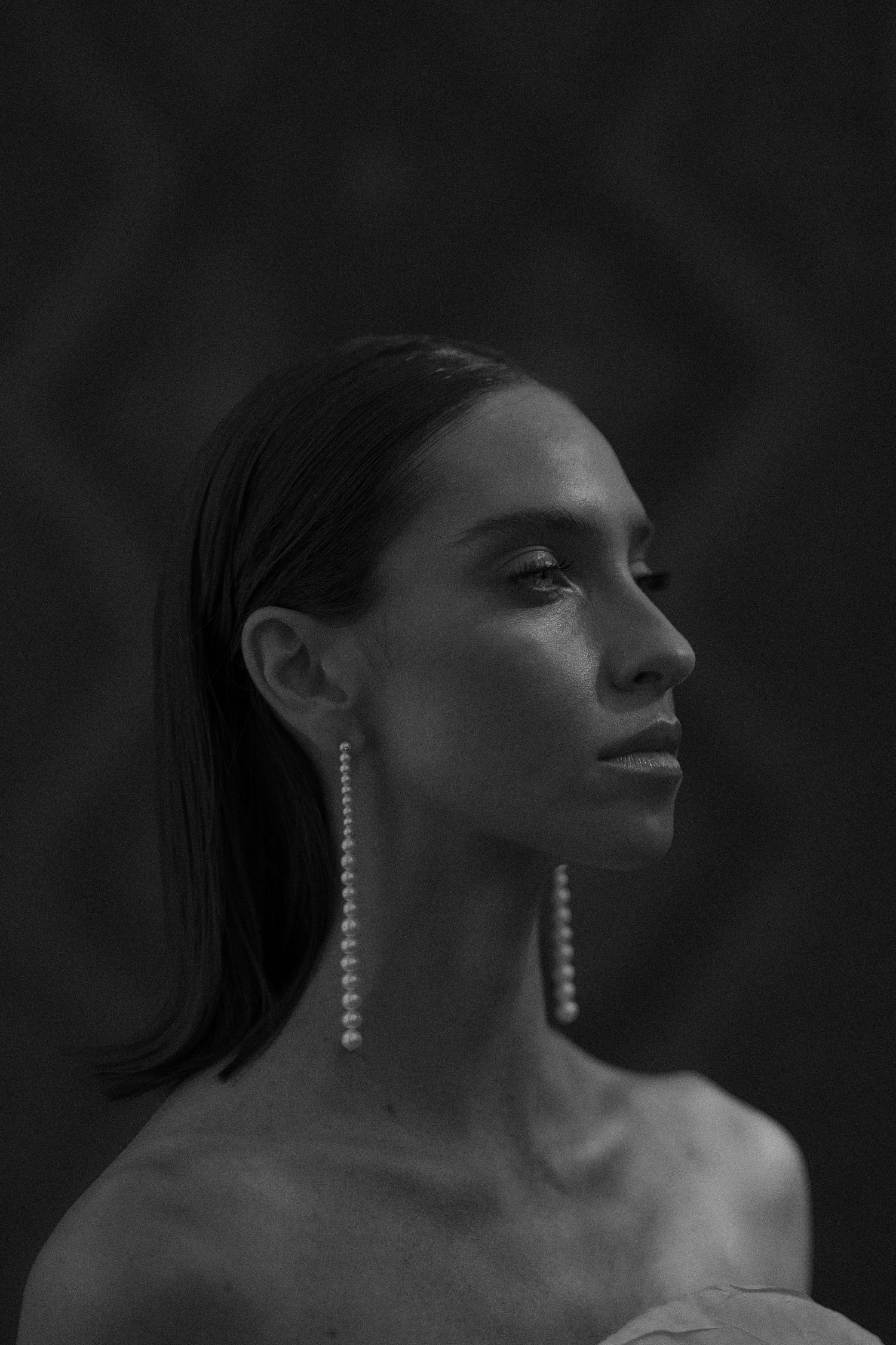 Dramatic black and white profile portraits showing elegant dangling earrings against dark background.