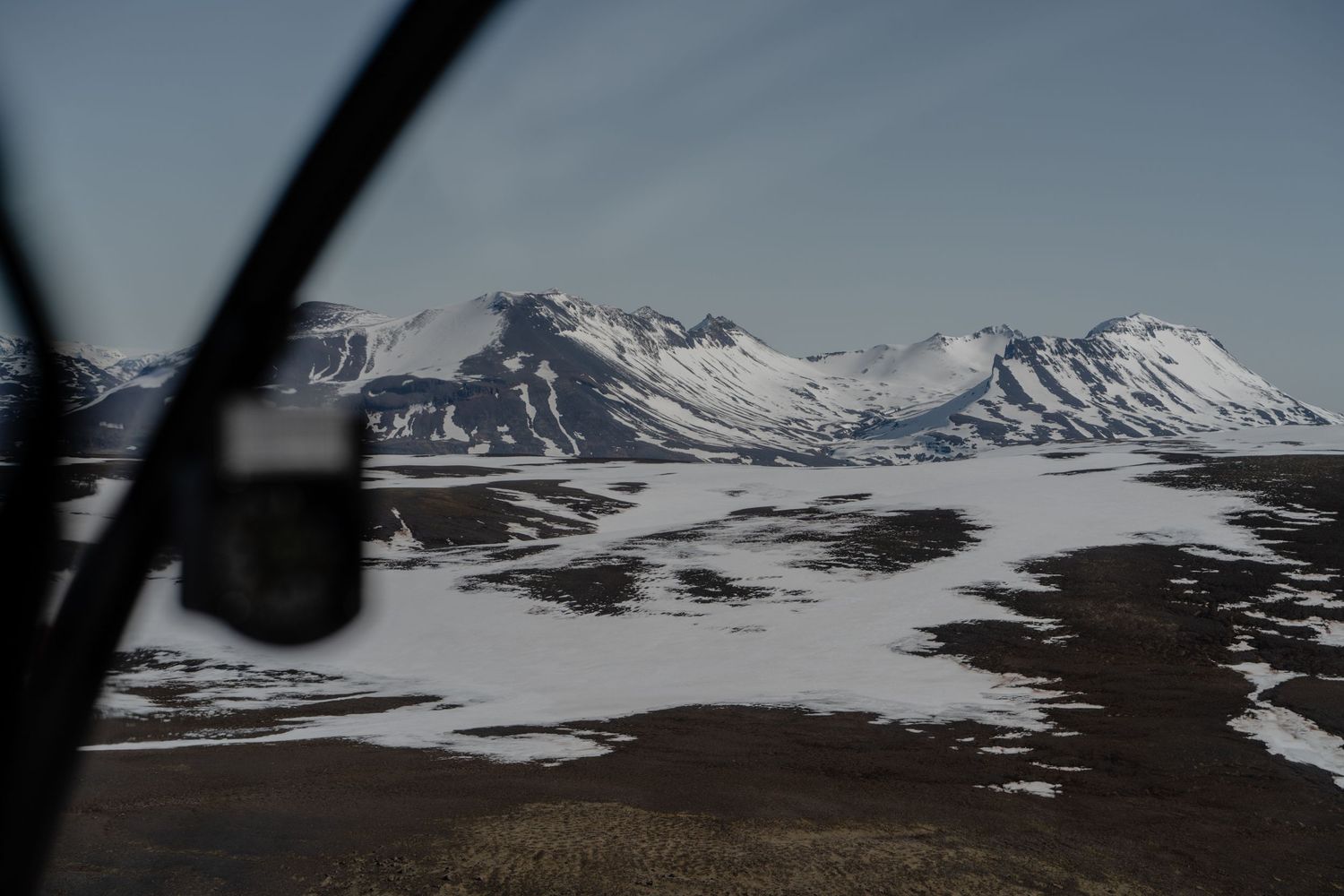 Aerial view of snow-covered mountains and glaciers under clear blue sky.