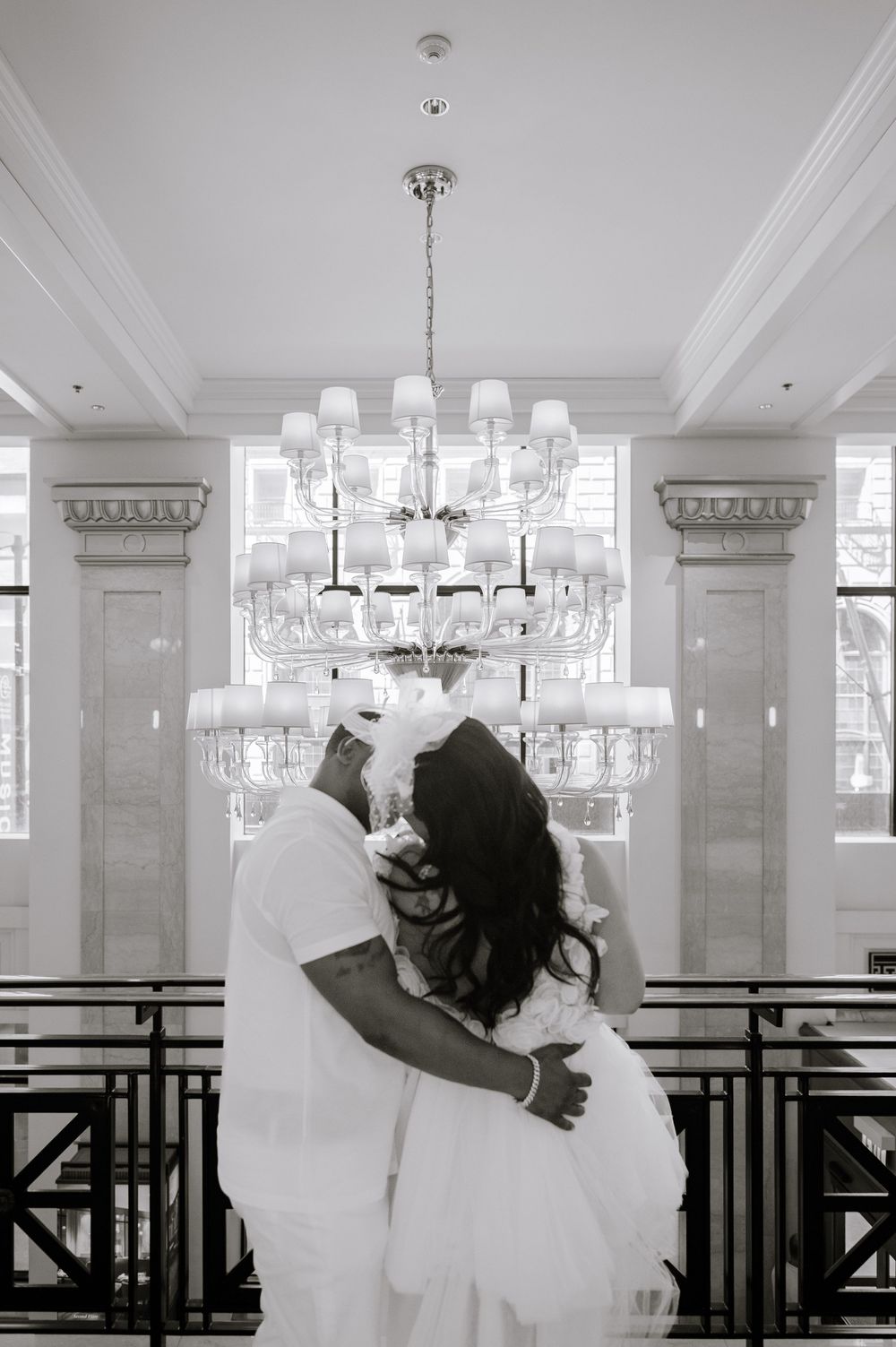 A romantic black and white photo sequence of a couple kissing in an elegant ballroom with crystal chandeliers.