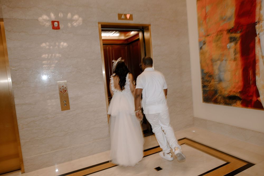 A series of elevator doors in a hotel hallway with beige marble walls and gold trim.